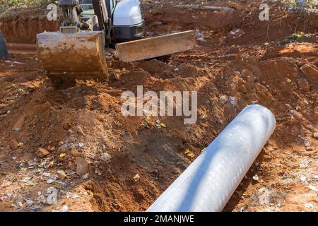 Il lavoratore che si prepara a lavorare con la posa di tubi di scarico in calcestruzzo nel terreno è prevenire l'allagamento sotterraneo. Foto Stock