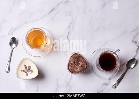 alcuni tè e cucchiai su un banco di marmo, con due tazze riempite con diversi tipi di tè Foto Stock