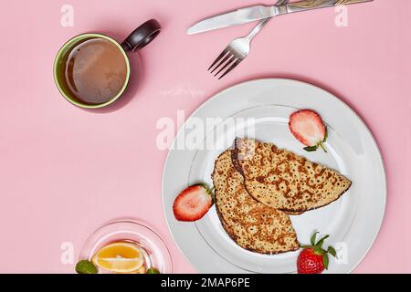 alcuni cibi su un piatto con una tazza di caffè e una forchetta accanto al piatto pieno di fragole Foto Stock
