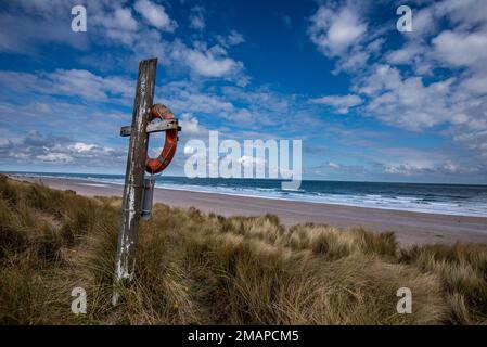 Lifebuoy si affaccia sulla spiaggia tra Seahouse e Bamburgh sulla costa del Northumberland. Foto Stock