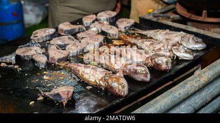 Filetti di pesce e pesce grigliati sulla superficie di ferro caldo, alimenti di mare di strada in Sri Lanka. Foto Stock