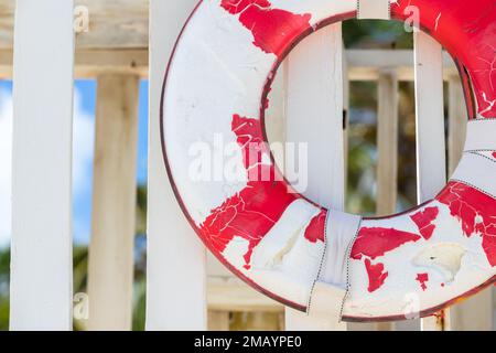 Foto in primo piano di una vecchia lifboa bianca rossa sullo sfondo sfocato della spiaggia Foto Stock