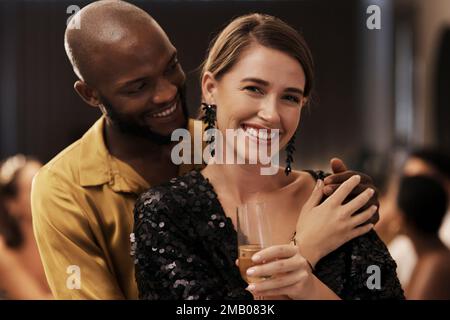 Comodamente innamorato. Una giovane coppia felice che sta vicino insieme durante una festa della cena di Capodanno. Foto Stock