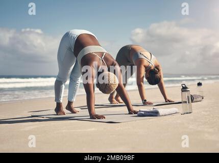 Lo yoga funziona una varietà di muscoli. due giovani donne che praticano lo yoga sulla spiaggia. Foto Stock