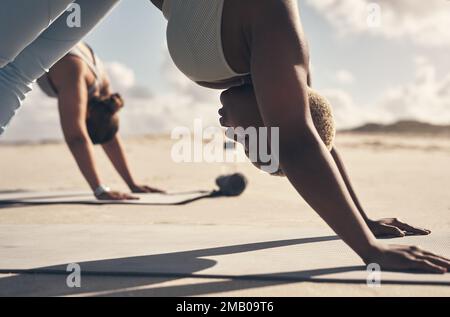 I buoni amici gireranno le loro vite capovolte per voi. due giovani donne che praticano lo yoga sulla spiaggia. Foto Stock