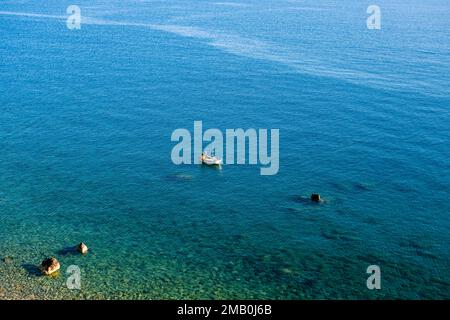 Veduta aerea di un pescatore, che lavora su una piccola barca sul mare di fronte alla cittadina di Castello di Tusa. Foto Stock