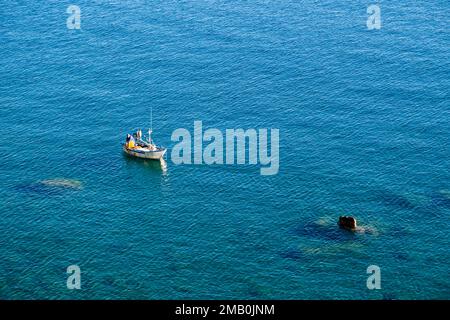 Veduta aerea di un pescatore, che lavora su una piccola barca sul mare di fronte alla cittadina di Castello di Tusa. Foto Stock