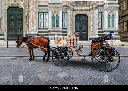 Carrozza trainata da cavalli dalla facciata in marmo colorato del Duomo o Cattedrale di Santa Maria del Fiore a Firenze, in attesa di turisti Foto Stock