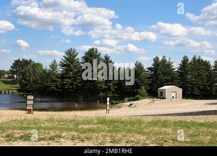 La spiaggia è mostrata il 9 giugno 2022, al lago Suukjak Sep presso il campeggio Pine View a Fort McCoy, Wisconsin. Il Pine View Campground fa parte della Pine View Recreation Area. Quest'area comprende anche Whitetail Ridge e Sportsman's Range. Il campeggio è immerso in una zona boscosa a circa 400 metri a ovest della zona di cantonment di Fort McCoy ed è delimitato dal lago Suukjak Sep a est e dal fiume la Crosse a ovest e a sud. Per ulteriori informazioni sulle tariffe di noleggio delle cabine, fai una sosta presso l'ufficio del campeggio o visita il sito https://mccoy.armymwr.com. Foto Stock