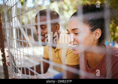 Coppia felice, recinto e sorriso al rifugio per animali, centro per animali domestici o zoo alla ricerca di un compagno carino da adottare. Uomo e donna neri sorridenti nella felicità Foto Stock