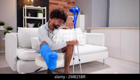 Gamba rotta in Cast Recovery. Uomo con ferita sul divano Foto Stock