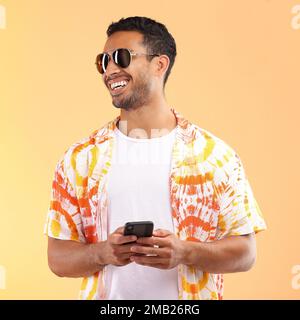 Occhiali da sole, telefono e uomo che scrive in studio isolato su uno sfondo giallo. Tecnologia, pensiero e modello maschile felice con smartphone mobile per Foto Stock