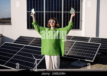 Felice proprietario della famiglia con soldi vicino alla centrale solare Foto Stock