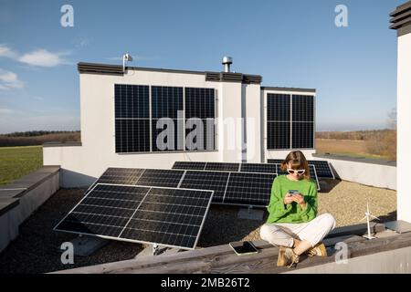 Donna sul tetto della sua casa con una pianta solare Foto Stock