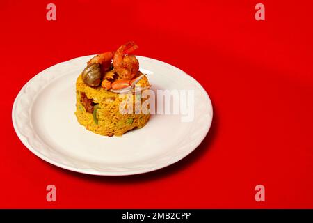 Arroz a la paella è una ricetta di cucina spagnola preparata in una grande padella con zafferano, frutti di mare come gamberi, vonghe, salsiccia, chorizo su un piatto bianco su un r Foto Stock