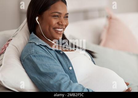 Godendo un certo tempo di chill durante il suo congedo di maternità. una donna incinta che ascolta musica mentre si rilassa a casa. Foto Stock
