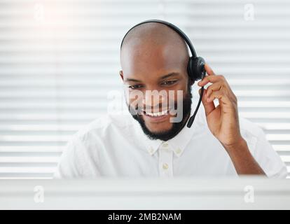 I nostri agenti sono sempre allegri. un bel giovane addetto alle vendite seduto da solo in ufficio e indossando una cuffia. Foto Stock