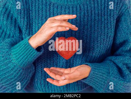 donna che tiene le mani dando la forma rossa del cuore. Persone, amore, carità, salute e concetto di famiglia. Foto Stock