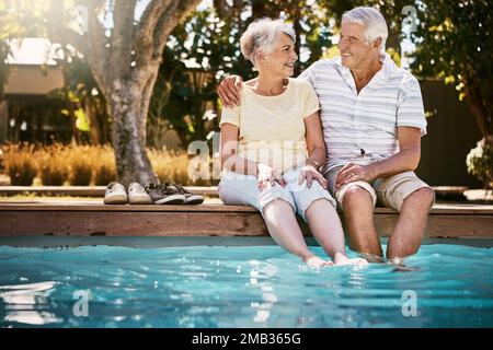 Coppia senior, abbraccio e piscina per le vacanze in relax per amore o di qualità tempo di legame insieme in vacanza estiva. Uomo anziano felice che tiene Foto Stock