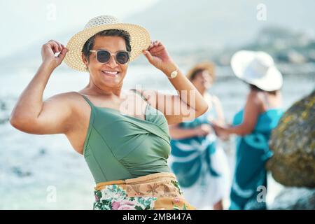 Rimanere giovani a cuore è come mantenere la vostra giovinezza. una donna matura attraente in piedi e in posa durante una giornata fuori sulla spiaggia con gli amici. Foto Stock