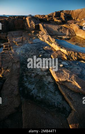 Rocce sulla spiaggia di Port Blanc nella luce del mattino, Bretagna, Francia Foto Stock