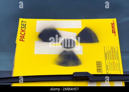 Segnale di radioattività sul pacchetto giallo, pacchetto DHL sul parabrezza, simbolo del trasporto di rifiuti nucleari, dimostrazione davanti all'ex energia nucleare Foto Stock