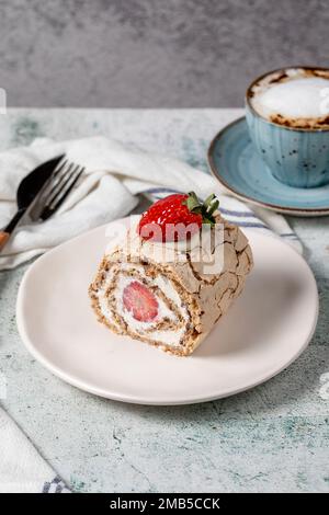 Torta al rotolo di fragole. Torta di log alla crema e alla fragola con caffè su fondo di pietra. primo piano Foto Stock