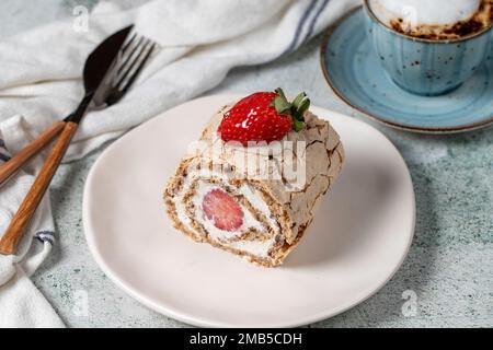 Torta al rotolo di fragole. Torta di log alla crema e alla fragola con caffè su fondo di pietra. primo piano Foto Stock