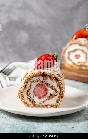 Torta al rotolo di fragole. Torta di log con crema e fragole su fondo di pietra. primo piano Foto Stock