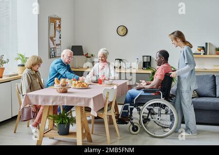 Gruppo di persone anziane sedute al tavolo e che fanno colazione in casa di cura Foto Stock