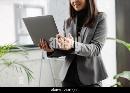Vista ritagliata di un designer sfocato che tiene il notebook in studio, immagine di scorta Foto Stock