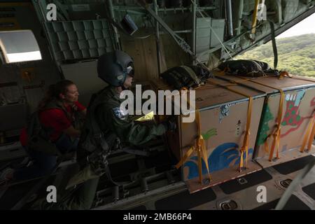 Japan Air Self-Defense Force staff Sgt. Ikkei Ono, 401st Tactical Airlift Squadron C-130H loadmaster, e Stati Uniti Britney Alonzo, 36th operazione sanitaria Squadron trica operazioni e l'amministrazione del paziente comandante di volo, spingere due pacchetti di assistenza umanitaria sull'isola di Murilo, lo stato di Chuuk, Stati Federati di Micronesia, 6 dicembre 2022, durante l'operazione Christmas Drop 2022. OCD è la più lunga missione umanitaria e di soccorso in caso di disastri del Dipartimento della Difesa. Ogni anno, l'USAF collabora con i paesi dell'area Pacific Air Forces di responsabilità Foto Stock