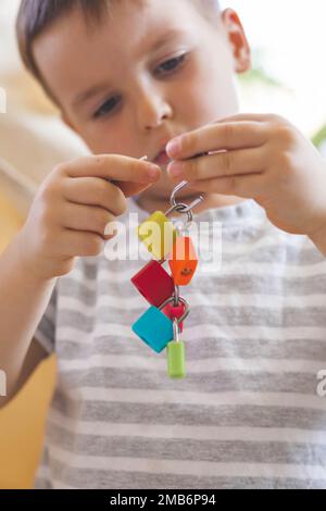 Il bambino lavora con materiale Montessori con serrature colorate. Raccoglie i tasti. Sviluppa le abilità motorie fini. Foto Stock