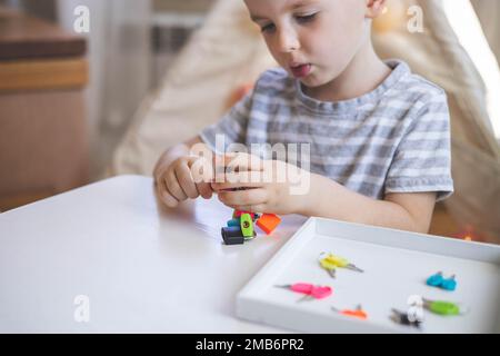 Il bambino lavora con materiale Montessori con serrature colorate. Raccoglie i tasti. Sviluppa le abilità motorie fini. Foto Stock