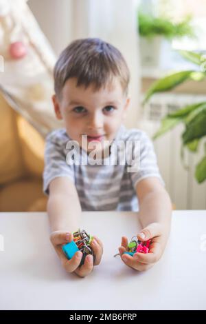 Il bambino lavora con materiale Montessori con serrature colorate. Raccoglie i tasti. Sviluppa le abilità motorie fini. Foto Stock