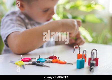 Il bambino lavora con materiale Montessori con serrature colorate. Raccoglie i tasti. Sviluppa le abilità motorie fini. Foto Stock