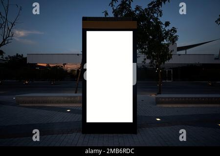 Mock up bianco di cartellone verticale del cartellone stradale sullo sfondo della città. Tabellone elettronico vuoto moderno sullo sfondo di una strada cittadina alla vigilia Foto Stock