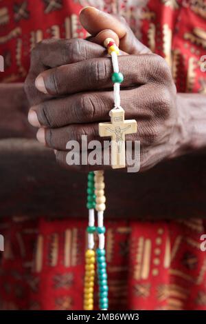 Africain price dans une église avec un chapelet. Cotonou. Bénin. Afrique. Afrique de l'Ouest. / Africano che prega in una chiesa con un rosario. Cotonou. Foto Stock