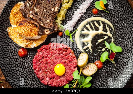 Tartare di manzo da Black Angus. Cipolla, uova di quaglia, salsa di pomodoro, maionese di senape. Delizioso e salutare primo piano di cucina italiana tradizionale servito per pranzo Foto Stock