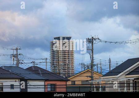 Alta torre di appartamenti su cavi elettrici e case suburbane Foto Stock