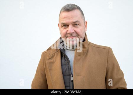Ritratto di un uomo serio di mezza età in un mantello marrone su uno sfondo bianco neutro Foto Stock