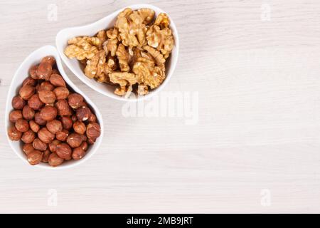 Nocciole e noci in ciotola bianca, concetto di sana alimentazione e stile di vita, luogo di testo o iscrizione Foto Stock