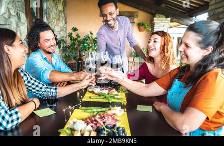 Amici felici che si divertono a bere al patio giardino della casa agricola - concetto di stile di vita con i giovani che si godono il tempo di raccolta insieme - degustazione di vino rosso Foto Stock