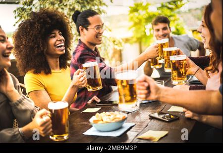 Persone multiculturali che bevono e tostano birra pinta al bar birreria ristorante - bevande concetto di stile di vita con il ragazzo e la ragazza che si divertono insieme Foto Stock