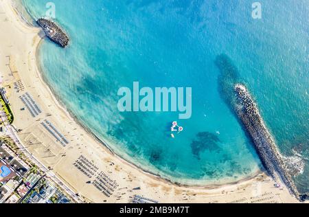 Veduta aerea della spiaggia della baia di Los Cristianos a Tenerife con lettini e ombrelloni in miniatura - concetto di viaggio con la natura meraviglia paesaggio a Canary islan Foto Stock
