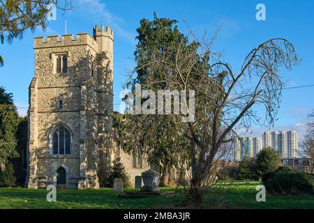 La torre e il cimitero di All Saints Church, Edmonton, North London, UK, con i blocchi torre sullo sfondo Foto Stock