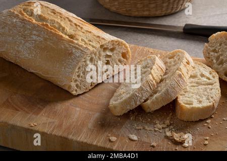 Tradizionale pane e fette di ciabatta al forno fresco italiano in un primo piano su un tagliere Foto Stock