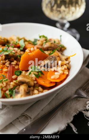 Zucca invernale con funghi, carote e orzo cotti al vino bianco. Foto Stock