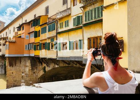 Una giovane donna che fotografa Ponte Vecchio a Firenze, Toscana, Italia, Europa Foto Stock