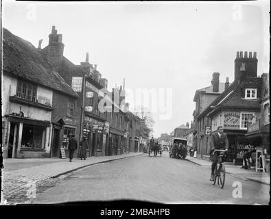 East Street, Farnham, Waverley, Surrey, 1909. Guardando verso nord-est lungo East Street a Farnham, mostrando un ciclista in primo piano e due carri trainati da cavalli che passano accanto ai negozi sullo sfondo. Nell'indice negativo della collezione, il fotografo ha registrato che un vecchio macellaio è mostrato nella fotografia, che sembra essere a sinistra del primo piano. Sono inoltre mostrati Farnham Cycle Works, i locali di W Ayling a 120 East Street e Rose &amp; Son corn Dealers a 6 East Street. Foto Stock